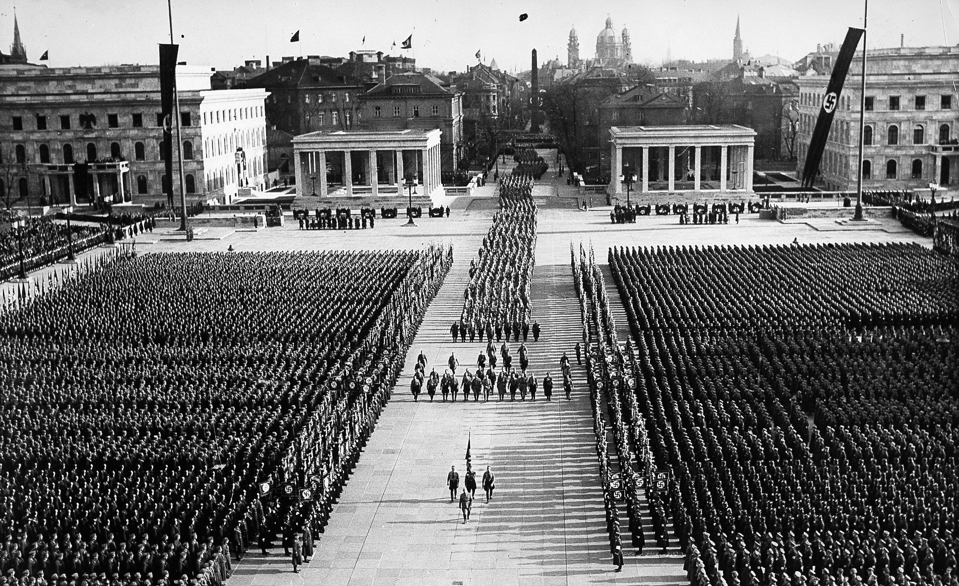 ハーケンクロイツ（ナチスの鉤十字）の旗と制服の集団が立ち並ぶケーニヒス広場の中央を、旗手に先導された葬列が通り抜ける。